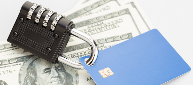 Pad lock hooked on a credit/debit card laying on top of cash