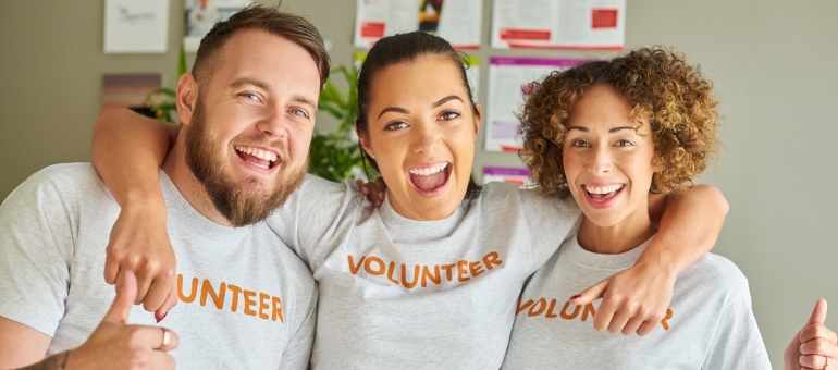 Three people standing close together with shirts that say "volunteer"