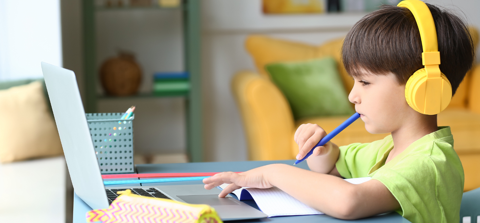 Young boy with laptop and yellow headphones in deep thought