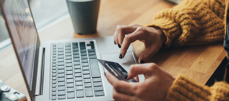 woman sitting at computer holding credit card