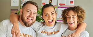 Three people standing close together with shirts that say "volunteer"
